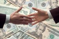 Two people shaking hands over money